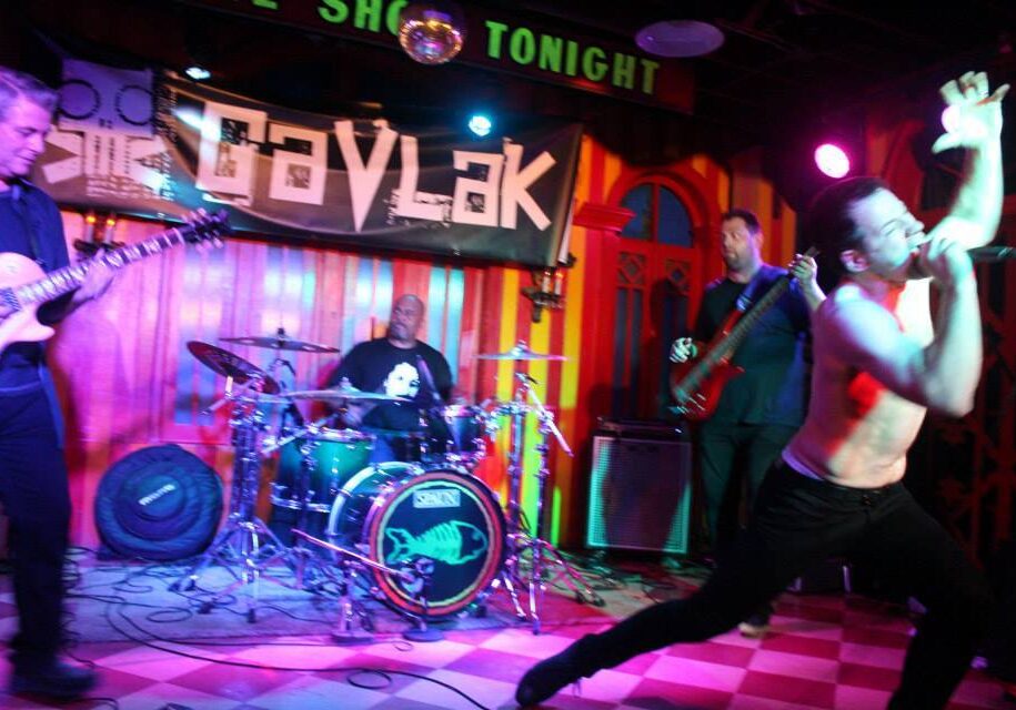 Live band performing energetically on stage with vibrant lighting.