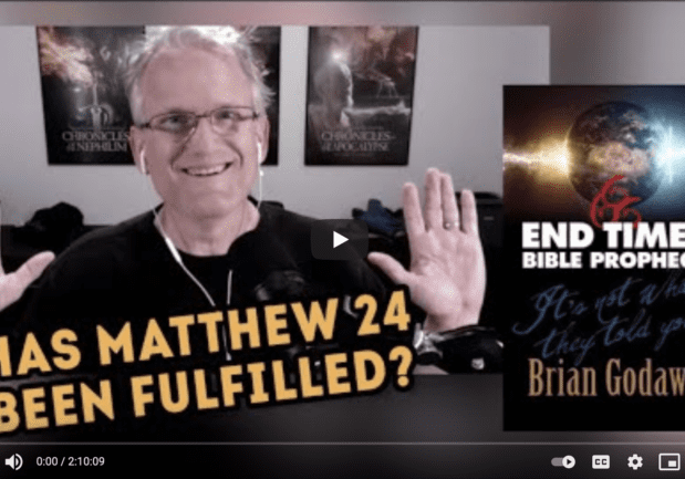 Smiling man raising hands beside Bible prophecy book